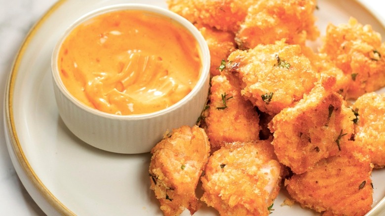 Plate of crispy salmon bites, next to a spicy dip