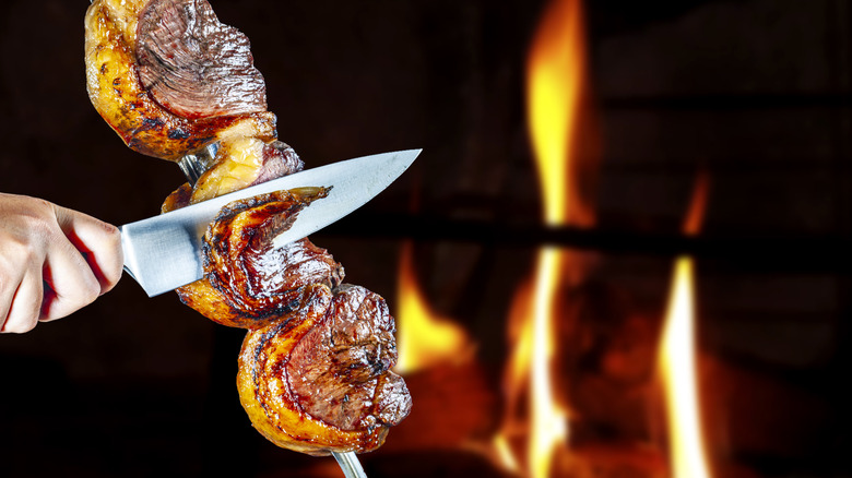 Person slicing meat off skewer