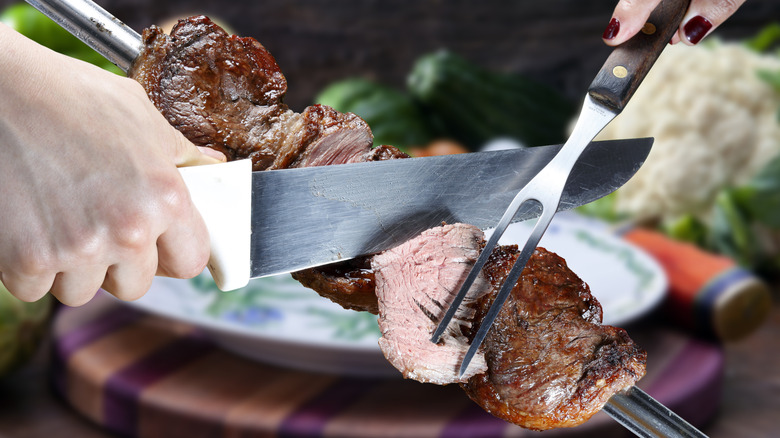 Person slicing beef at Brazilian steakhouse