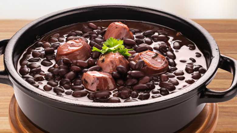 Brazilian feijoada in black bowl on wooden table