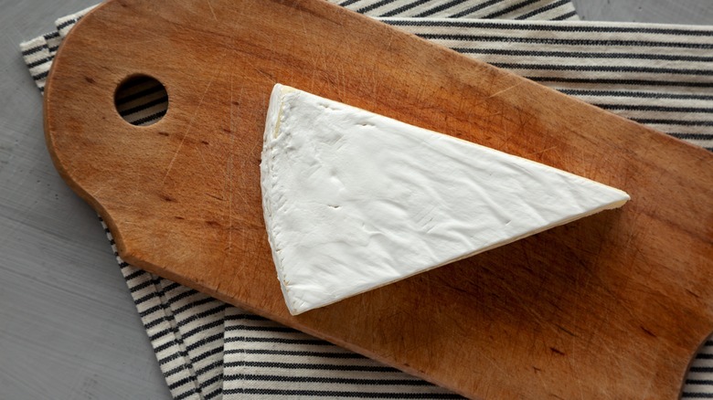 Wedge of brie on wooden board