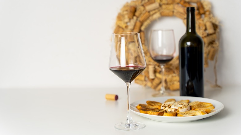 Glasses and bottle of red wine, with baked brie and bread