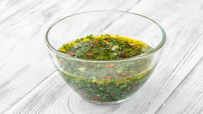 Glass bowl of chimichurri covered with oil