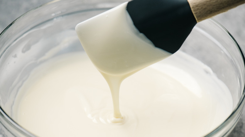 White royal icing running off a black spoon