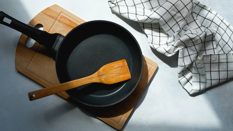 Cast iron pan with spatula, cutting board, and kitchen towel
