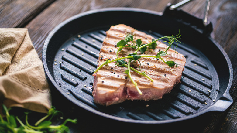 Cooked tuna steak in a skillet, with herbs