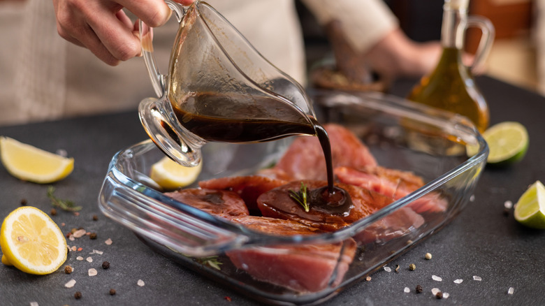 A chef pours a soy-based marinade onto tuna steaks