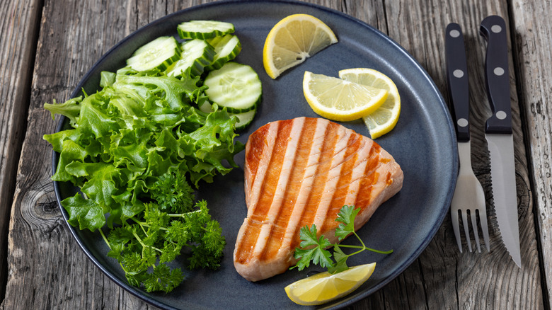 Grilled tuna steak with fresh salad and lemon wedges