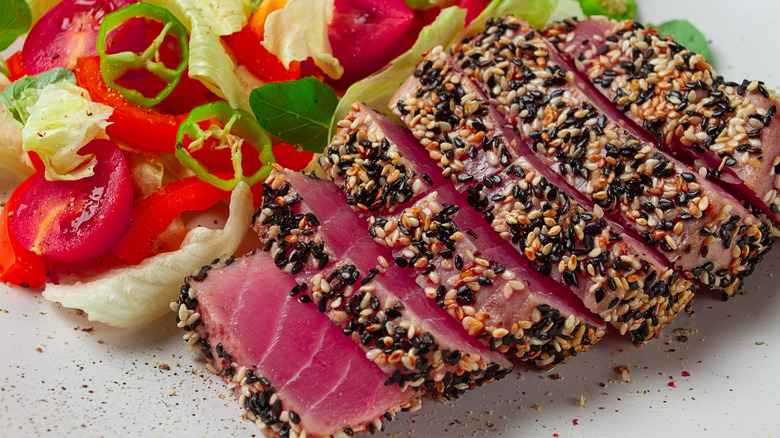 Lightly seared tuna steak encrusted with sesame seeds, with a side salad