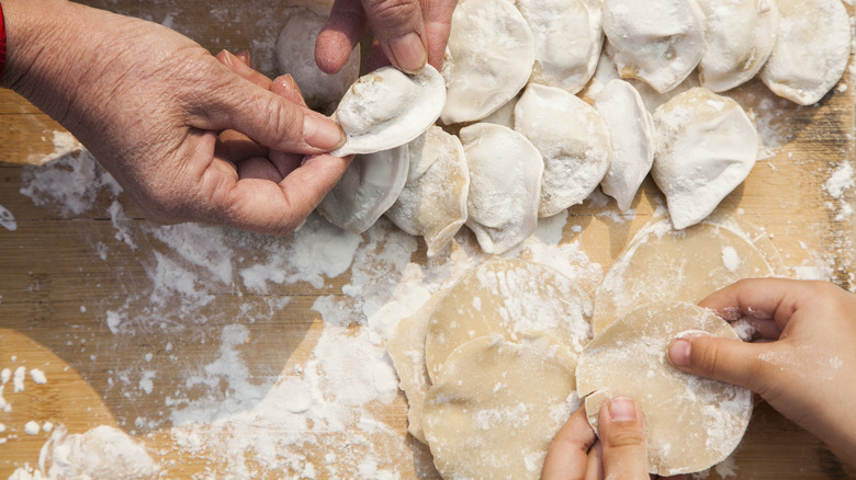 people preparing uncooked dumplings