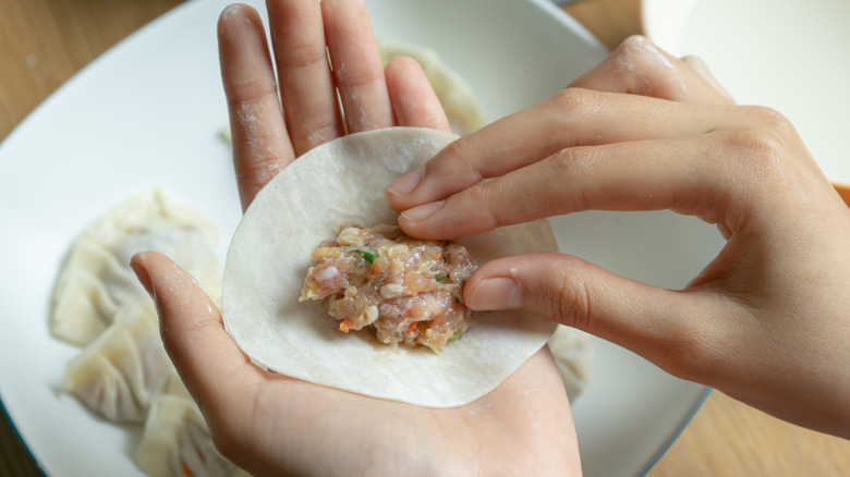 person adding filling to dumpling