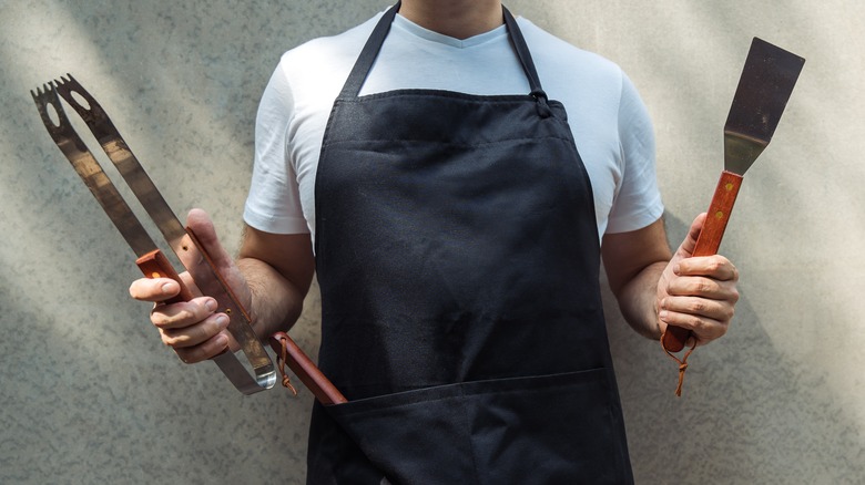 man holding barbecue tools