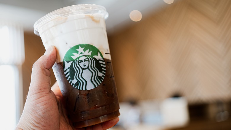 Person holding Starbucks iced coffee with foam