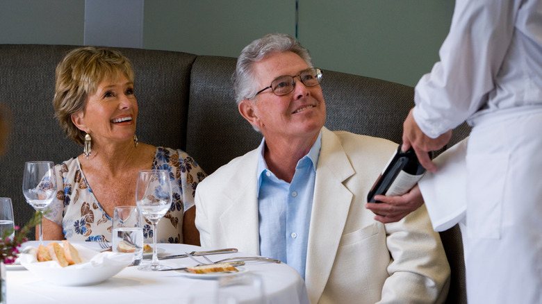 server presenting couple with a bottle of wine