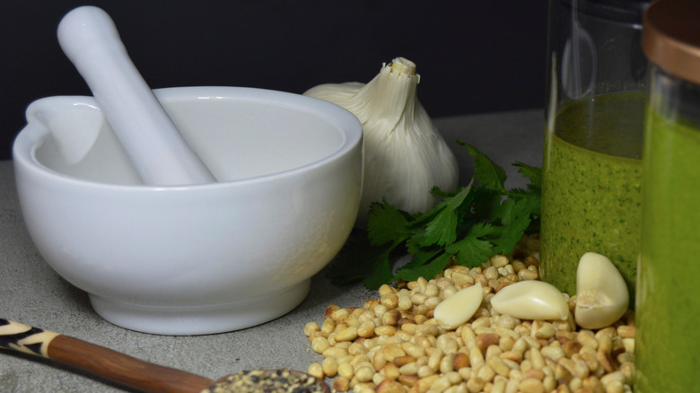white pestle and mortar with pesto ingredients