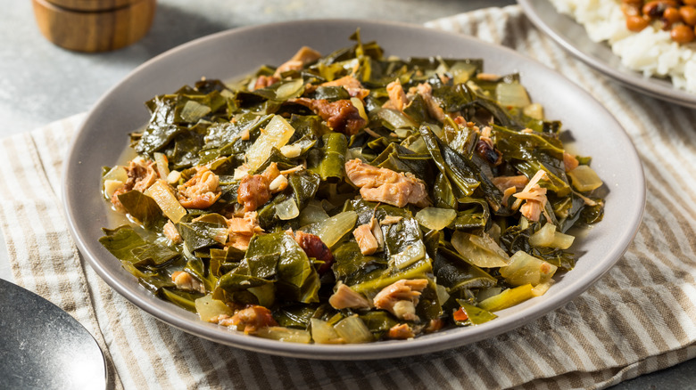 bowl of stewed collard greens on a white table.