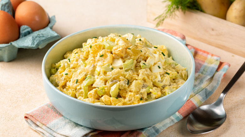 a bowl of potato salad on colorful gingham towel on a wooden table
