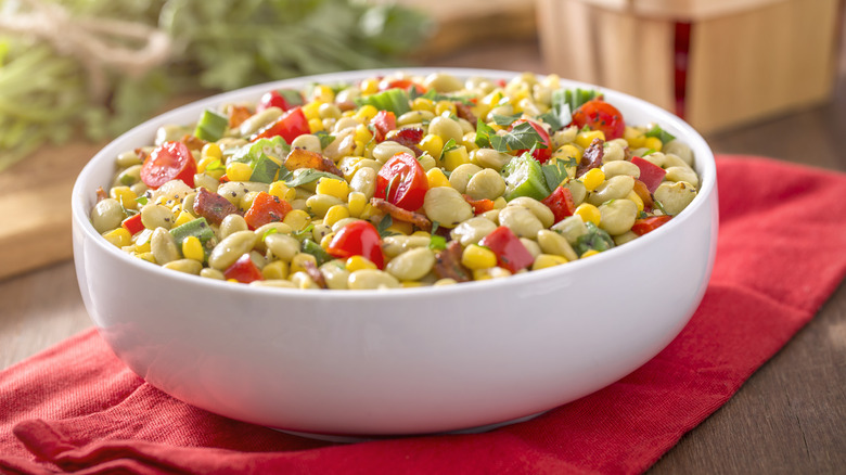 a bright bowl of succotash on a red towel.