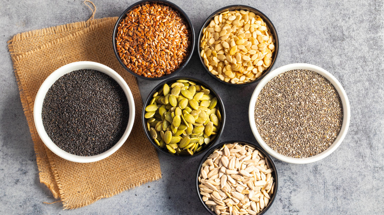 A few types of seeds in bowls on a rustic table