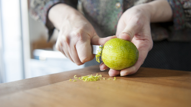 Woman using a scraper to zest a lime