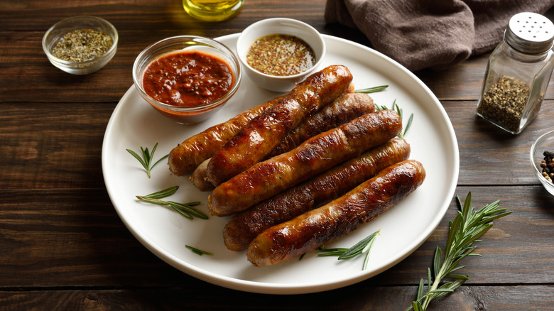 Plate of grilled sausages, with tomato and mustard dipping sauces