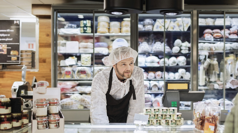 Deli employee wearing hairnet while leaning over counter