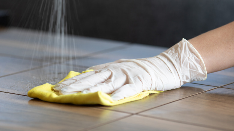 Gloved hand disinfecting surface