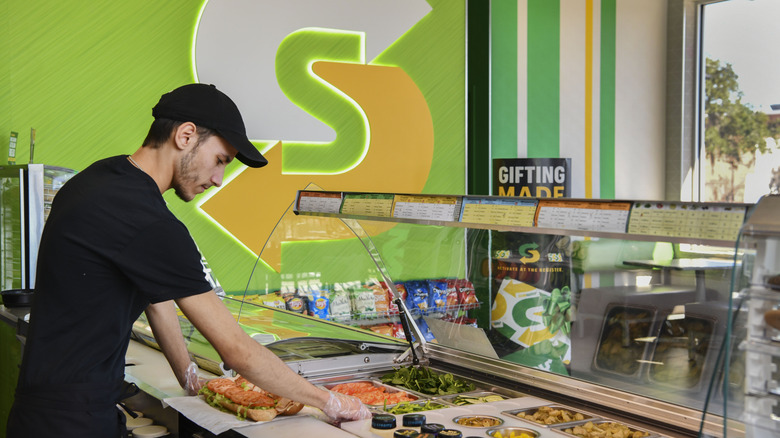 Subway worker assembling a sandwich at the counter