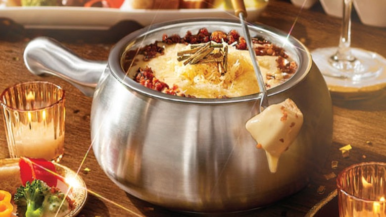Fondue pot filled with cheese, with a piece of dipped bread on a fork