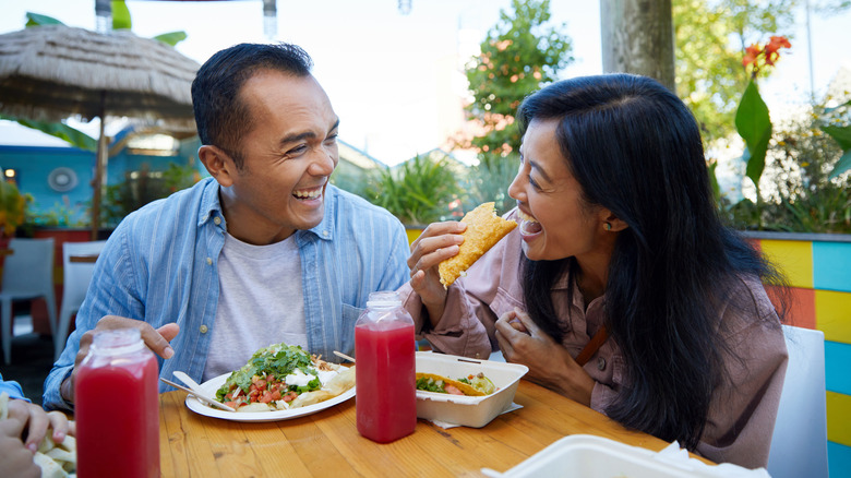 Happy couple smiling with woman eating a taco
