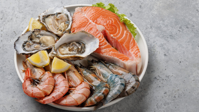 A raw seafood platter including salmon, oysters, and prawns