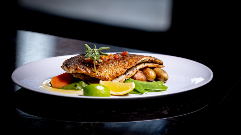 A fillet of fried fish served in a restaurant with vegetables and potatoes
