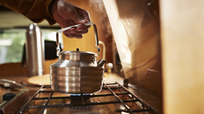 man puts metal kettle on stove