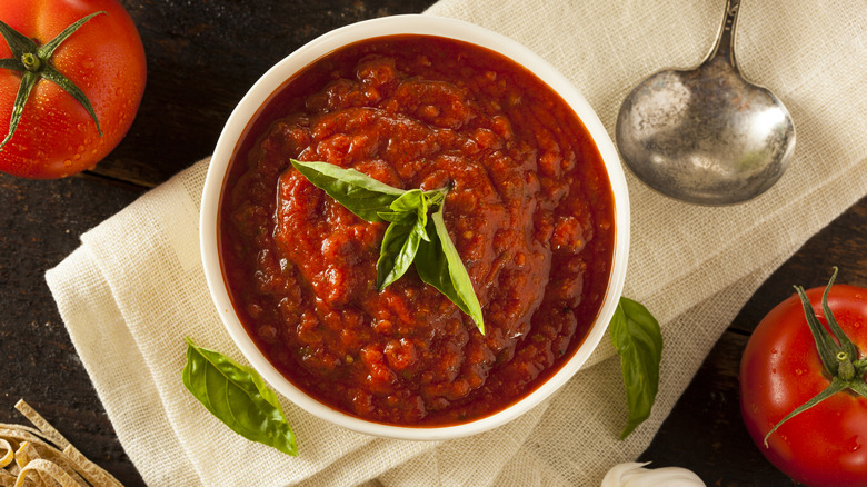 Bowl of marinara sauce surrounded by ingredients