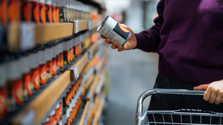 A woman looks at soup cans in the grocery store