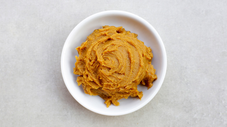 A white bowl is filled with yellow miso paste.