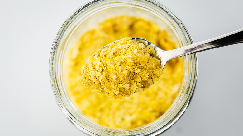 Nutritional yeast is being spooned out of bowl.