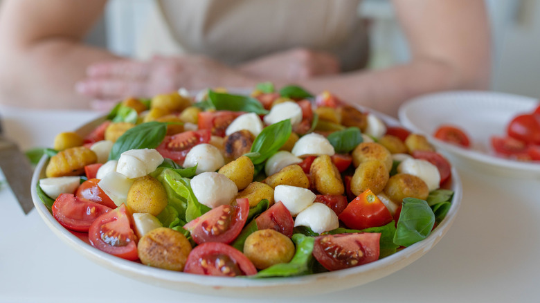 Salad of chopped tomatoes, toasted gnocchi, green leaves and mozzarella pieces