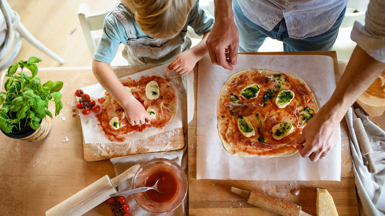 A mother and child making pizzas from scratch