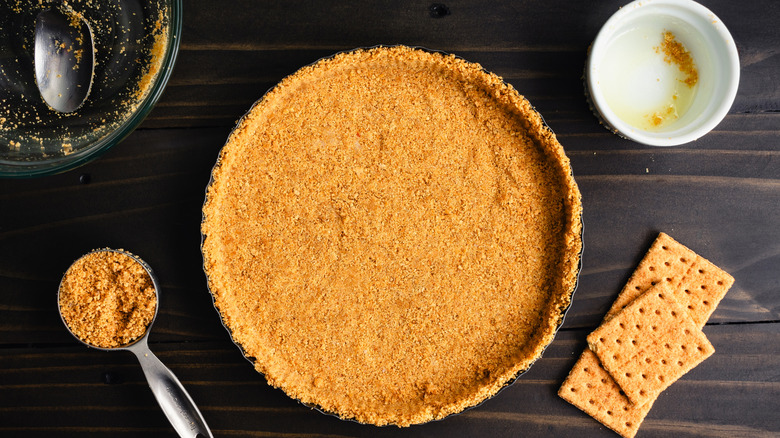 A pie tin lined with a graham cracker crust