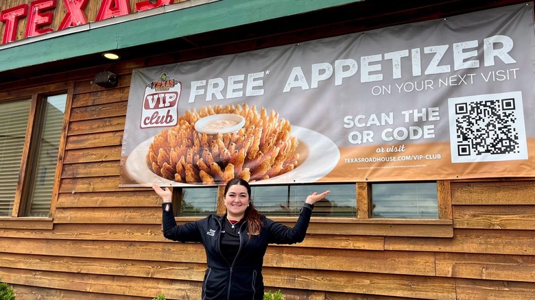 Woman posing next to a banner advertising the Texas Roadhouse VIP Club