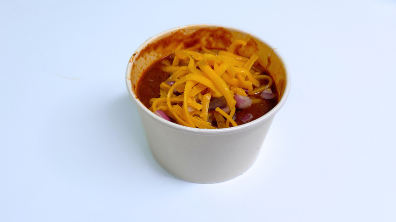 A side of chili with cheese isolated on a whitish-blue background