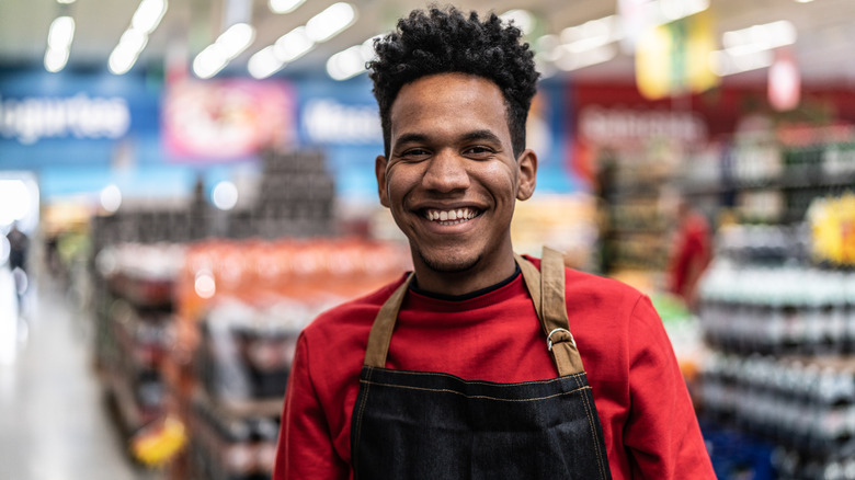 Smiling store employee, wearing a red jumper with an apron over the top