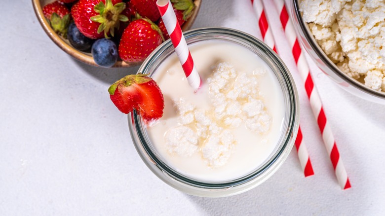 Smoothie topped with cottage cheese, with berries and colorful straws