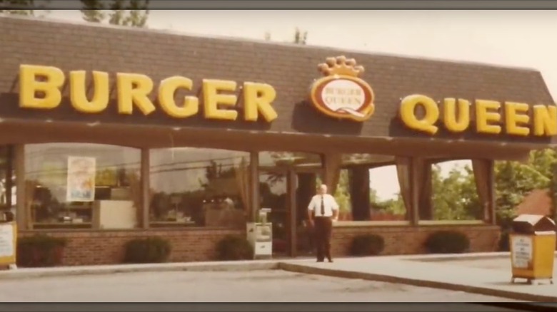 Burger Queen restaurant exterior, with a man standing outside it