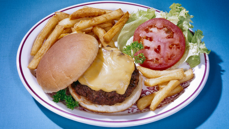 A vintage image of a cheeseburger, fries, and a salad
