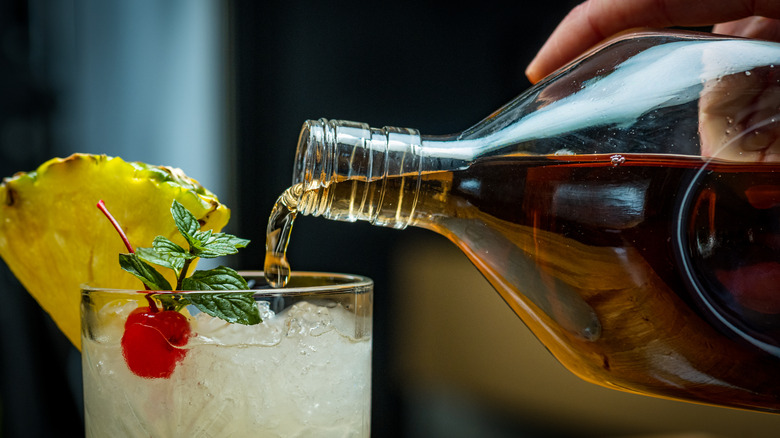 person adding rum to cocktail