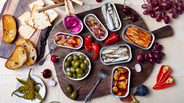 wooden board with various cans of fish and other food