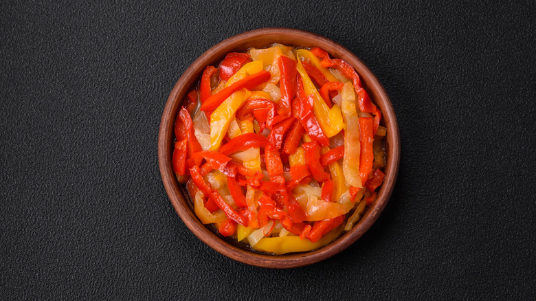 Sautéed onions and red and yellow peppers in an earthenware bowl
