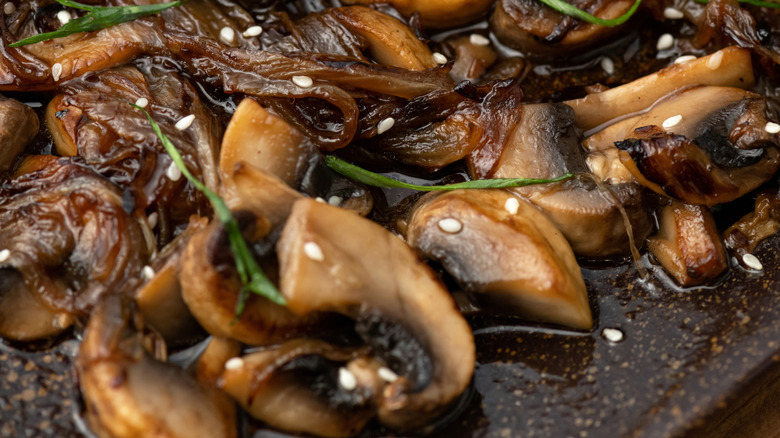 Close-up of sautéed mushrooms with caramelized onions, herbs, and sesame seeds